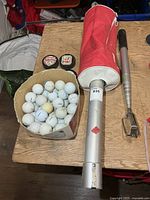 Group view showing extendable retriever, shag bag with tube, box of golf balls, two hockey pucks