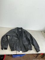 Front view of DNK black leather jacket displayed on table