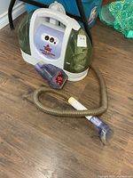 Full view of Bissell Little Green ProHeat cleaner with hose and brush