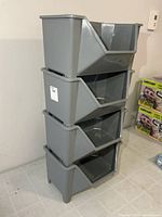 Four grey plastic bins stacked side view