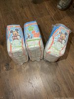 Three packs of Disney-themed Huggies Pull-Ups diapers on wood floor