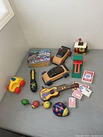All items arranged on table showing variety of toys, puzzle tin, playing cards