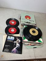 Stack and spread of 45 rpm records, some in sleeves, Elvis picture sleeve visible