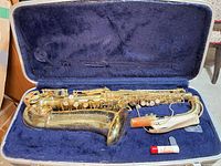 Alto saxophone in blue-lined hard case with mouthpiece and cork grease visible