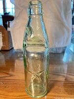Full view of aqua Codd-style bottle standing upright showing star embossing and marble in neck