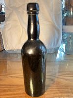 Full view of dark amber hand-blown bottle showing applied blob top and body