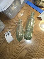 Two aqua glass torpedo bottles side by side on table