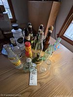 Overall view of 14 assorted vintage glass bottles on tabletop