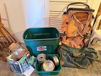 Overview of all items: backpack, duffel, totes, boxed Coleman lantern, cookware
