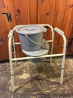 Full view of gray Guardian bedside commode with bucket, lid and padded arms