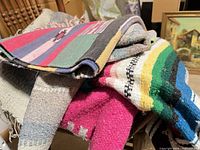 Pile of five woven blankets showing variety of colours and patterns
