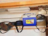 Shelf view showing four coolers: brown soft cooler, black soft cooler, Igloo Playmate Elite hard cooler, gray/black/brown soft cooler