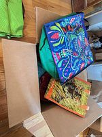 Open box showing multiple reusable bags including blue folk floral print, green zippered bag, tiger photo print bag