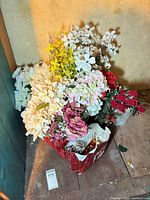 Crate filled with mixed artificial flowers and bag of ornaments