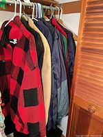 Group of coats and jackets hanging in closet showing colours and styles