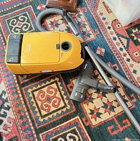 Top view of yellow Miele canister vacuum with hose, wand and floor head