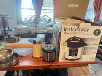 Lot overview with boxed Instant Pot, grinder, rolling pin, pots, glass jar