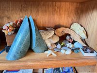 Shelf showing green stone bookends, minerals, shells, driftwood, specimen box