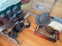 Multiple shoe pairs on metal rack, hat on box, boots in box