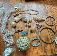 Overview of entire lot on wood surface showing necklaces, earrings, bangles, brooches, pins, ring, bookmark and trinket box