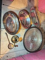 Group shot showing two oval platters, pierced bread tray, round glass dish with metal rim, ladle, candle holder