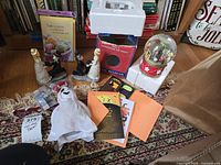 Full lot overview showing all major items including waterglobe, skeleton figurines, card packs, ghost plush, vampire teeth, bagged figures