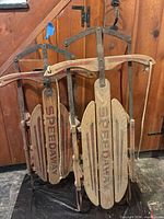 Front view of both wooden sleds standing upright showing SPEEDWAY branding and red accents