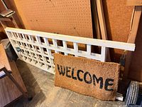Wood lattice panels and coir doormat leaning against wall.