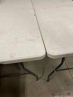 top view of two white folding tables joined side by side showing surface wear