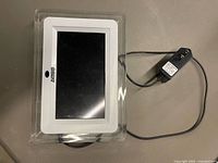 Front view of Sony digital photo frame with screen off and attached power adapter