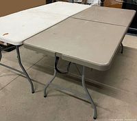 White and beige folding tables side by side showing tops and legs