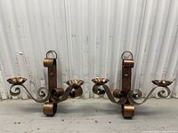 Front view of both metal wall sconces showing scroll arms and finish