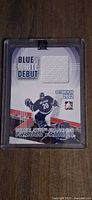 Front of Ed Belfour Blue and White Debut trading card with jersey swatch