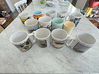 Group shot of 13 assorted mugs on countertop displaying various designs