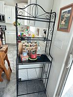 Full view of matte black metal baker’s rack with dark top shelf and three wire shelves