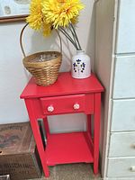 Front view of red side table with basket, vase and flowers