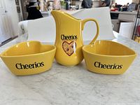 Front view of pitcher and two bowls showing Cheerios logos and heart graphic