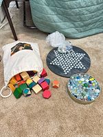 Bag of wooden blocks, Chinese-checkers board, tin of marbles, loose marbles
