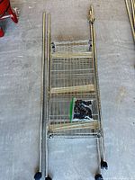 Full set showing four wire shelves stacked with vertical poles and casters