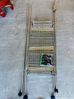 All components laid out: three wire shelves, top frame, four poles with casters, bag of plastic clips
