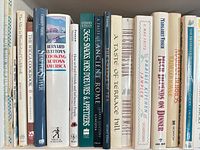 Shelf view showing multiple cookbook spines with mixed hardcover and paperback bindings