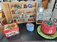 overview of lot showing wooden shadowbox with miniatures, two tins, tomato bowl with plate and metal étagère