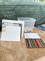 Group shot showing paper pads, colored pencils, paint tubes in storage tub