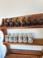 Shelf with 7 dark brown and 7 light gray rabbit figurines
