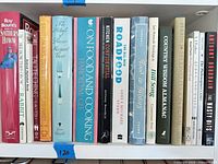 Books spines visible showing assorted cookbooks, travel food guides, humor and essays