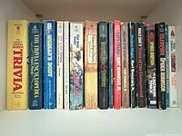 Row of 18 paperback books showing spines and wear