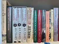 Shelf view showing thirteen hardcover and trade paperback Tolkien titles including A Tolkien Bestiary, The Hobbit, The Silmarillion, Unfinished Tales, The Book of Lost Tales, Children of Húrin