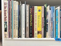 Shelf view showing first half of the book lot, titles include Off the Beaten Path, National Parks of the West, Back Roads of California, Grand Canyon National Park, Weird Washington