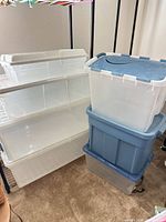 Stack of seven plastic storage bins showing variety of colors and sizes