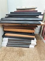 Stack of mixed black, wood tone, white frames showing quantity